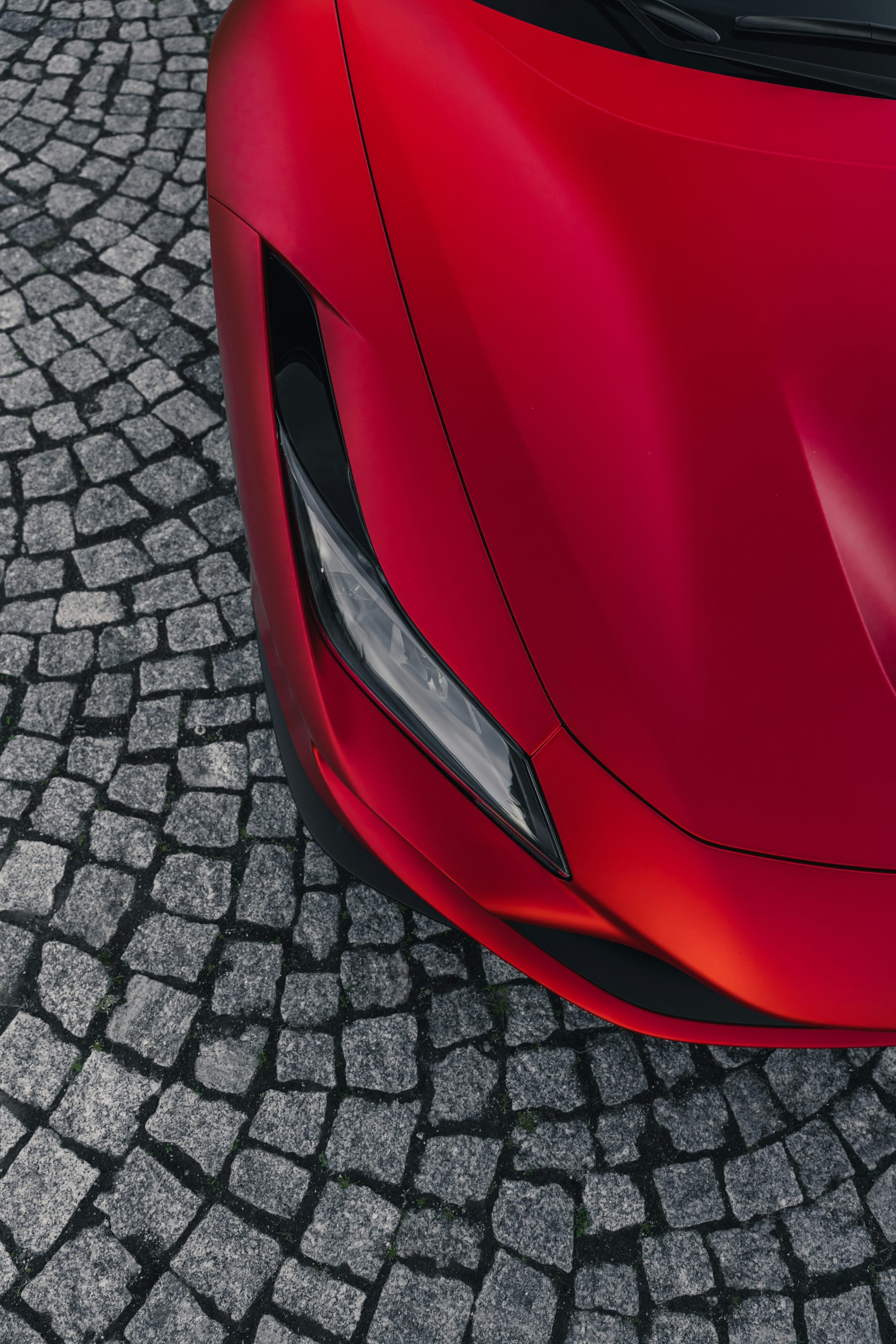 a red sports car parked on a cobblestone street